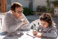 Close up portrait of old teacher supervising little kid doing homework outdoors. Beautiful girl doing homework with the Royalty Free Stock Photo