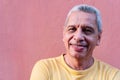 Close up portrait older Hispanic man leaning against wall and staring