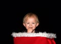 Baby boy smiling with fingers in mouth sitting in Christmas basket looking at viewer Royalty Free Stock Photo