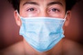 Close up and portrait of one millennial teenager man looking at the camera sad wearing mask ad crying for the covid-19 Royalty Free Stock Photo