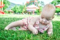 Close up. Portrait of a one year old 9 month old toddler in a pink sundress. She lies on a lush green lawn Royalty Free Stock Photo