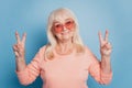 Close up portrait of pensioner lady showing two v-signs