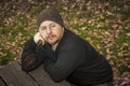 Close up portrait pensive man with wool hat sitting on a bench. Royalty Free Stock Photo