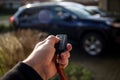 A close up portrait of a person holding a car key in his hand pressing the unlock button. The keyless remote control has unlock Royalty Free Stock Photo