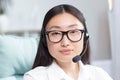 Close-up portrait photo of Asian female call center worker and tech support worker, looking at camera and smiling, using Royalty Free Stock Photo