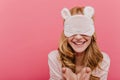 Close-up portrait of playful white woman in sleepmask posing with sincere smile. Enthusiastic girl in night-suit