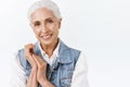 Close-up portrait pleasant, charming old modern lady, senior woman with grey hair in stylish denim vest, touching hands