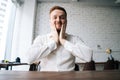 Close-up portrait of positive handsome young business man sitting at desk in modern office room and smiling looking at Royalty Free Stock Photo