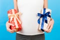 Close up portrait of pregnant woman in home clothing holding two gift boxes at blue background. Waiting for a baby boy or a baby Royalty Free Stock Photo