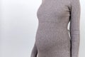 Close up portrait of pregnant woman`s belly at gray background. Mother is wearing gray dress. Motherhood concept. Copy space Royalty Free Stock Photo