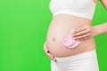 Close up portrait of pregnant woman in white underwear holding pink socks for a baby girl at green background. Waiting for a child Royalty Free Stock Photo