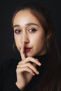 Close up portrait of pretty beautiful young woman wearing black sweater isolate over dark background. Quiet posing. Silence