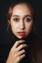 Close up portrait of pretty beautiful young woman wearing black sweater isolate over dark background. Woman using red lipstick.