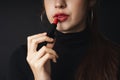 Close up portrait of pretty beautiful young woman wearing black sweater isolate over dark background. Woman using red lipstick.