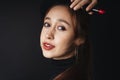 Close up portrait of pretty beautiful young woman wearing black sweater isolate over dark background. Woman using red lipstick.