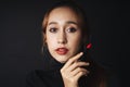 Close up portrait of pretty beautiful young woman wearing black sweater isolate over dark background. Woman using red lipstick.