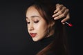 Close up portrait of pretty beautiful young woman wearing black sweater isolate over dark background. Woman using red lipstick.