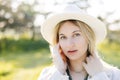 Close up portrait of pretty blond woman in white hat posing in forest. White summer clothes Royalty Free Stock Photo