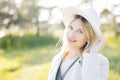 Close up portrait of pretty blond woman in white hat posing in forest. White summer clothes Royalty Free Stock Photo