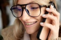 Close up portrait of pretty blonde woman dressed warm clothes talking on phone. Big Beautiful smile with teeth and Royalty Free Stock Photo