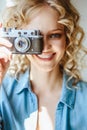 Close up portrait of pretty blonde young woman with old vintage camera in her hands Royalty Free Stock Photo