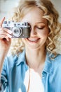 Close up portrait of pretty blonde young woman with old vintage camera in her hands Royalty Free Stock Photo