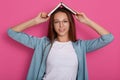 Close up portrait of pretty brunette holding open text book organaizer over her head, adorable female wearing white casual shirt, Royalty Free Stock Photo