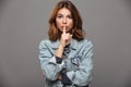 Close-up portrait of pretty brunette woman in casual wear showing silence gesture, looking at camera Royalty Free Stock Photo