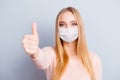 Close-up portrait of pretty healthy blonde girl wearing safety mask giving thumbup isolated on gray color background