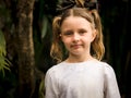 Close up portrait of pretty little girl. Blue eyes and blond hair. Caucasian girl with two ponytails. Dark brown background Royalty Free Stock Photo