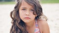 Close-up portrait of a pretty little Hispanic girl with waving in the wind long hair sitting on the beach. Royalty Free Stock Photo