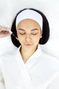 Close up portrait of a pretty peaceful girl in a white bathrobe is doing a cosmetic procedure