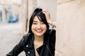 Close-up portrait of pretty smiling girl with long brunette ponytail hair, wearing black leather jacket, posing to