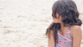 Close-up portrait of a pretty little Hispanic girl with waving in the wind long hair sitting on the beach. Royalty Free Stock Photo