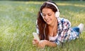 Close up portrait of pretty young girl listening music lying at the grass Royalty Free Stock Photo