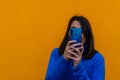 Close-up portrait of pretty young girl using mobile taking pictures snap isolated over orange color background Royalty Free Stock Photo