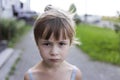 Close-up portrait of pretty young little blond pale unhappy moody friendless child girl looking sadly in camera on blurred sunny o Royalty Free Stock Photo