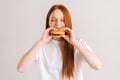 Close-up portrait of pretty young woman with closed eyes enjoying bite of appetizing delicious hamburger on white Royalty Free Stock Photo