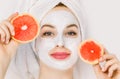 Close up portrait of pretty young woman with towel on head, having clay mud mask on her face, and holding slices of Royalty Free Stock Photo