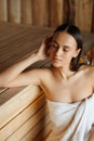 Close up portrait of pretty young woman in white towel relaxing in sauna. Royalty Free Stock Photo