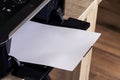 A close up portrait of a printer with an empty white piece of paper in its printed output tray. The blank page can be used to Royalty Free Stock Photo