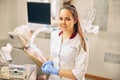 Charming European dentist in blue gloves sitting in the clinic