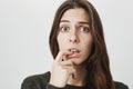 Close-up portrait of puzzled confused woman with dark long hair dressed casually, looking at camera with puzzlement