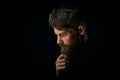 Close-up portrait of puzzled young man touching beard looking do