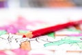 A close up portrait of a red pencil lying on a coloring book for adults. The page is already a bit colored in, but some parts are Royalty Free Stock Photo