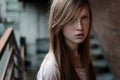 Close-up portrait of a redhead girl with freckles and blue eyes standing on the stairs and looking at camera