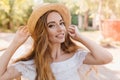 Close-up portrait of refined lady in trendy summer hat smiling on blur nature background. Outdoor photo of pretty long Royalty Free Stock Photo
