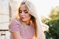 Close-up portrait of romantic girl with long blonde hair relaxing on balcony in sunny day. Charming young woman with Royalty Free Stock Photo