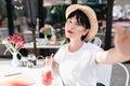 Close-up portrait of romantic girl with pale skin and dark hair chilling in cozy outdoor cafe with flowers on table Royalty Free Stock Photo