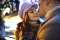 Close-up portrait of romantic stylish couple in warm clothes close to each other and kissing, standing against ice rink Royalty Free Stock Photo